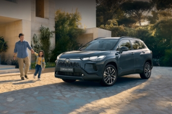Mężczyzna trzyma dziecko za rękę i razem idą w stronę zaparkowanej Toyoty Corolla Cross