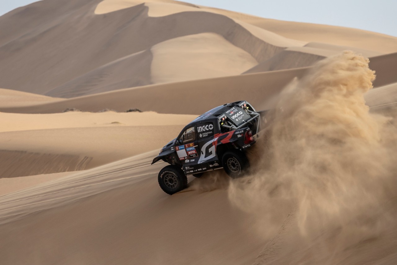 Hilux jadący przez pustynię, wzbijający piasek